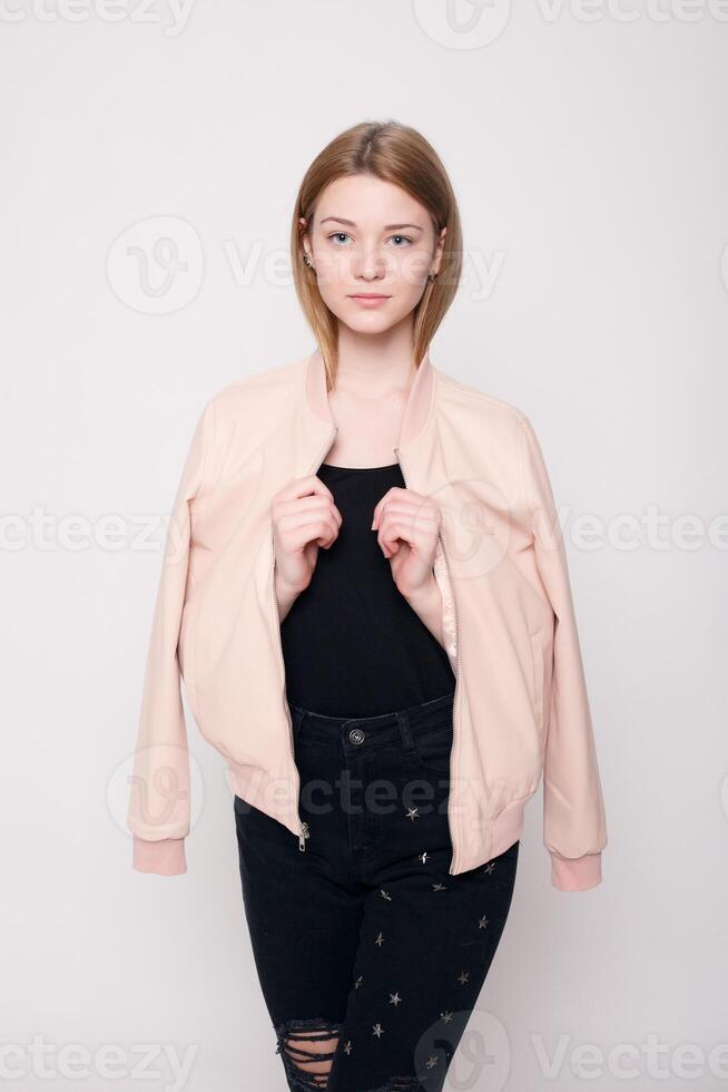 Fashion young woman smiles, confused looking at the camera on a gray background photo