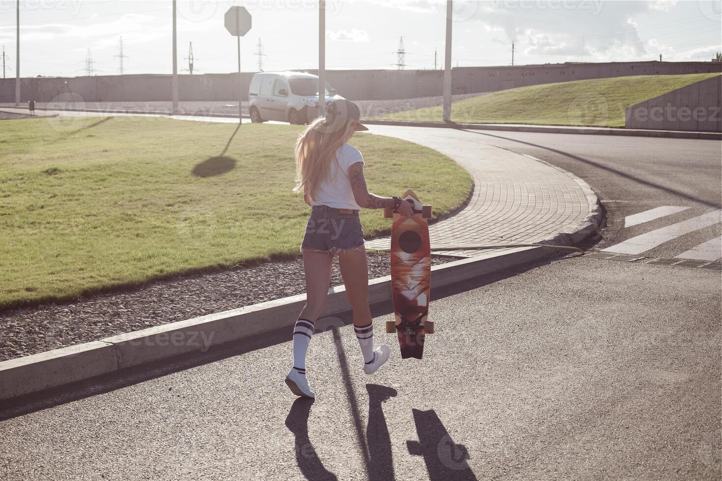 retrato de un hipster joven niña sonriente con un longboard a puesta de sol. foto