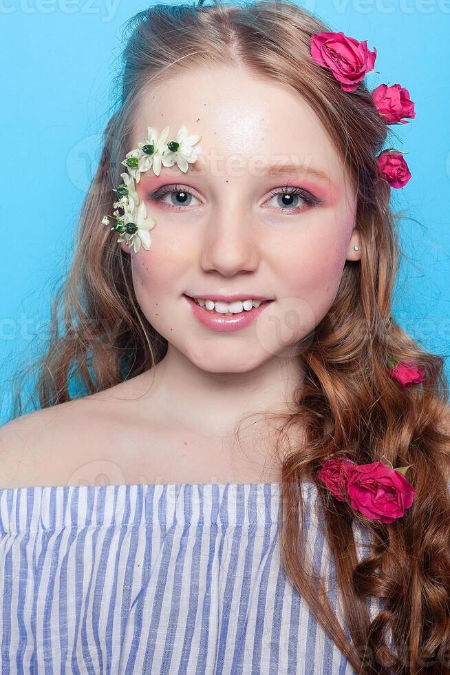 positivo muchacha. pequeño niña con margaritas en su manos en un azul antecedentes. foto