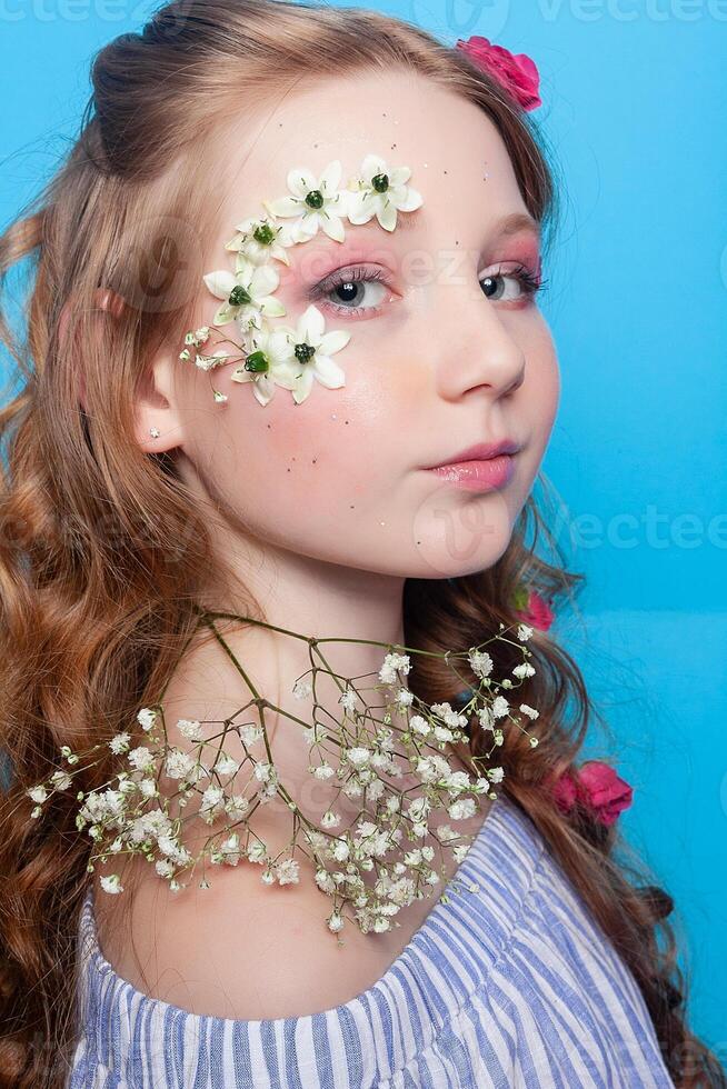 Positive girl. Little girl with daisies in her hands on a blue background. photo