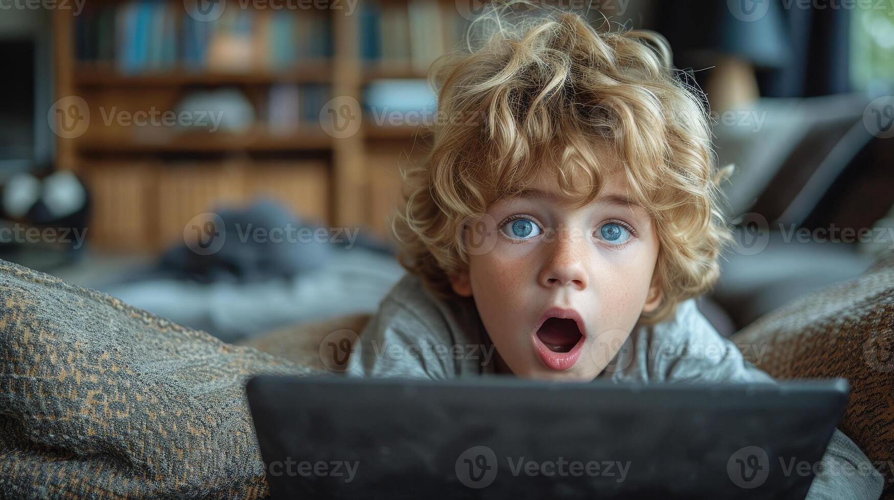 AI Generated The beautiful blond schoolboy boy is sitting on the sofa with a laptop and shouting at the screen. Remote education for children during quarantine. photo