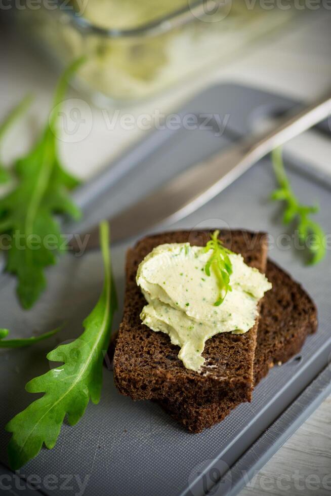 bread cheese spread with garlic and arugula on dark bread photo