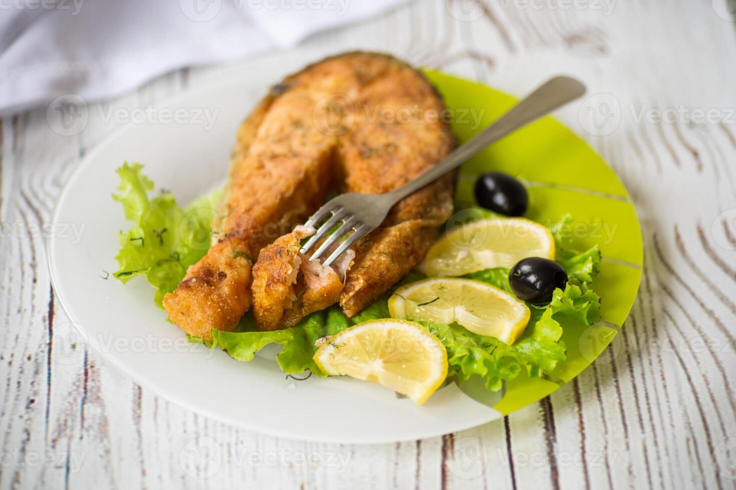 pedazo de frito salmón pescado en un plato con limón foto