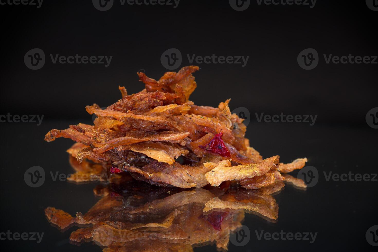 handful of dried meat marinated with spices, isolated on a black background. photo