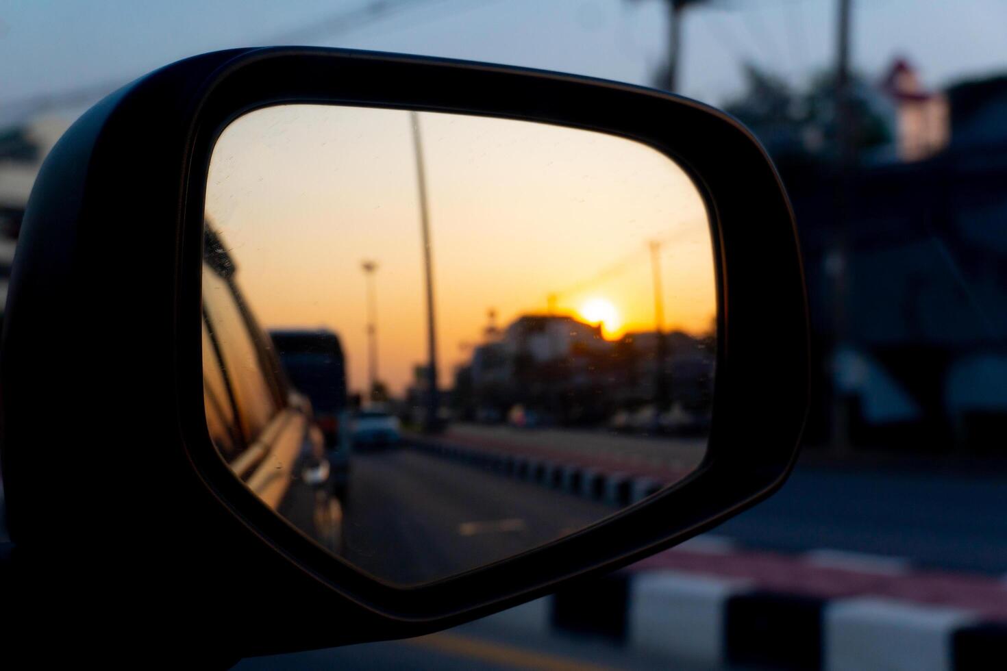 Reflection of the sunset in the car of side mirror view in Thailand. car on the road heading towards the goal of the trip. photo