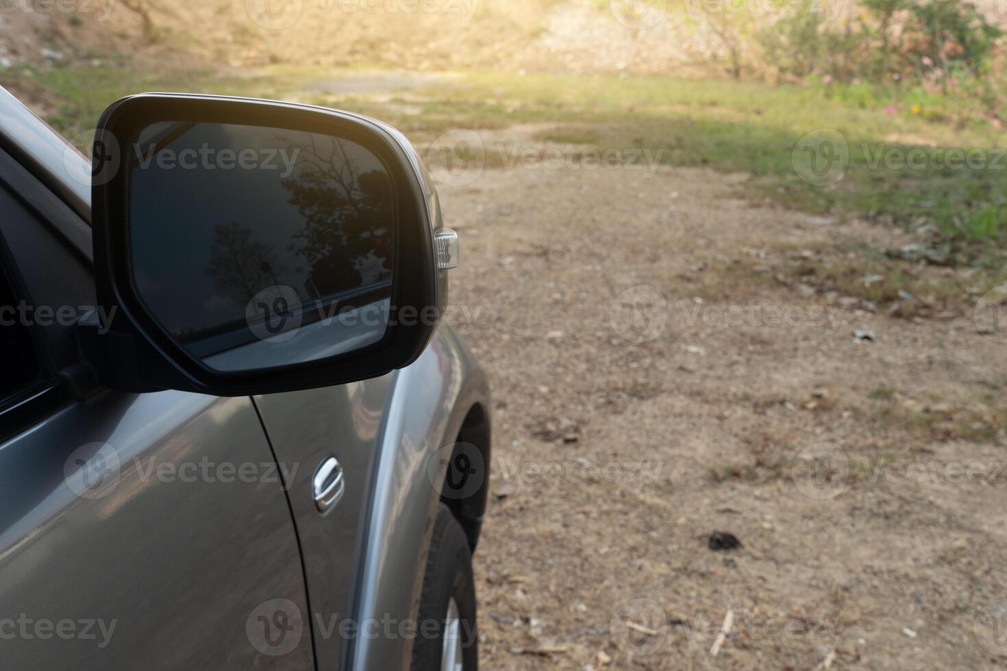 Car on the road in the countryside, view from the side mirror with fron car. Background of soil and green grass on the ground. photo