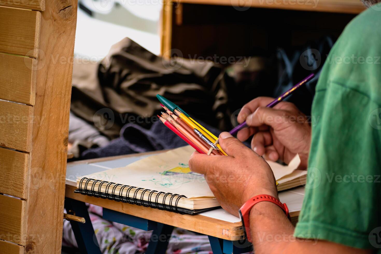 Man drawing on a notebook and holding pencils on a table in a converted van photo