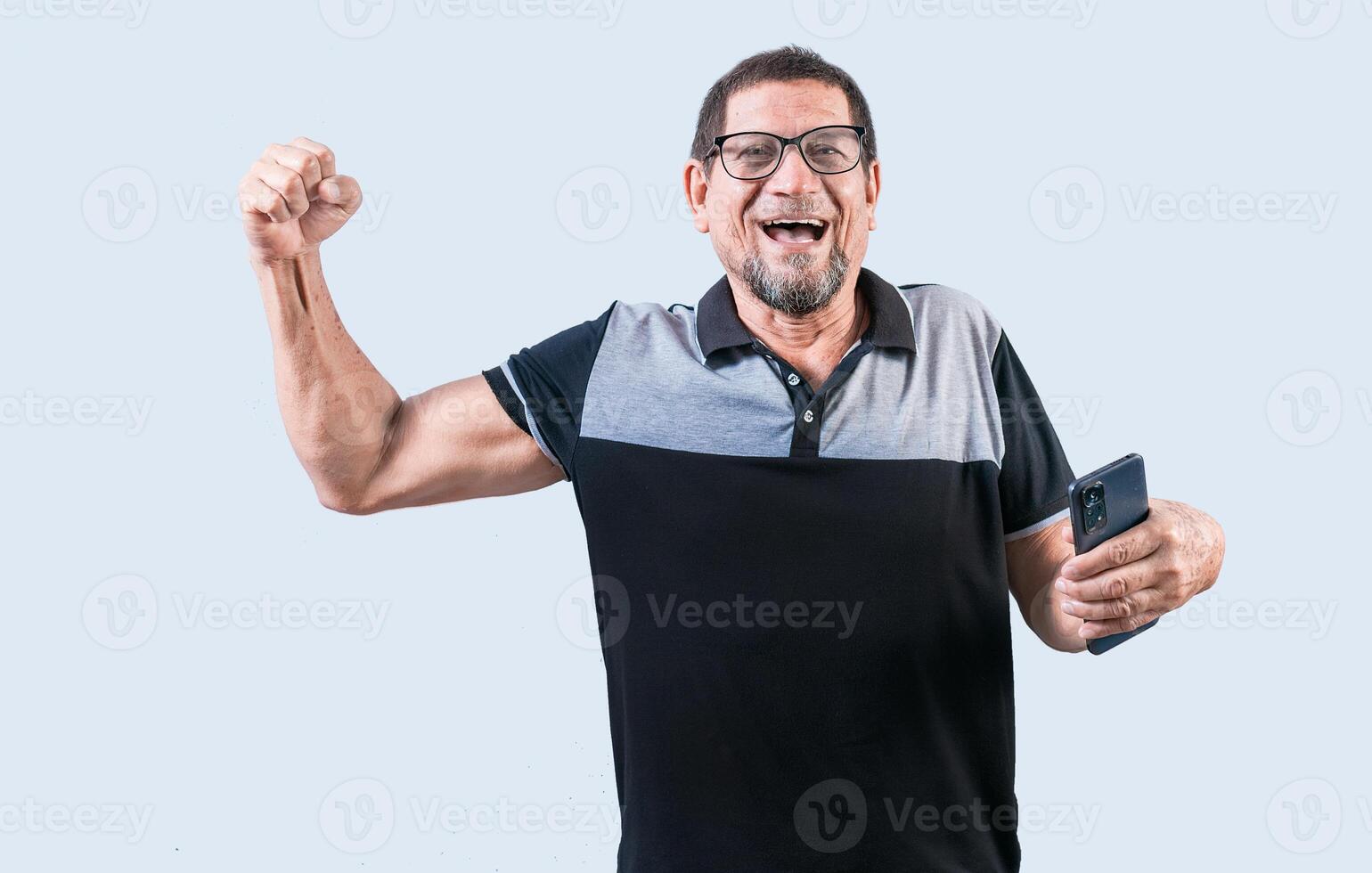 Happy winner senior man holding cell phone isolated. Senior person celebrating and holding phone isolated. Happy people holding smartphone and celebrating photo