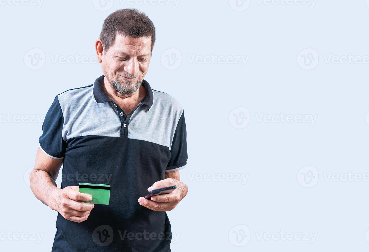 Smiling senior man holding credit card and smartphone isolated. isolated. Cheerful senior man shopping online holding credit card and smartphone photo