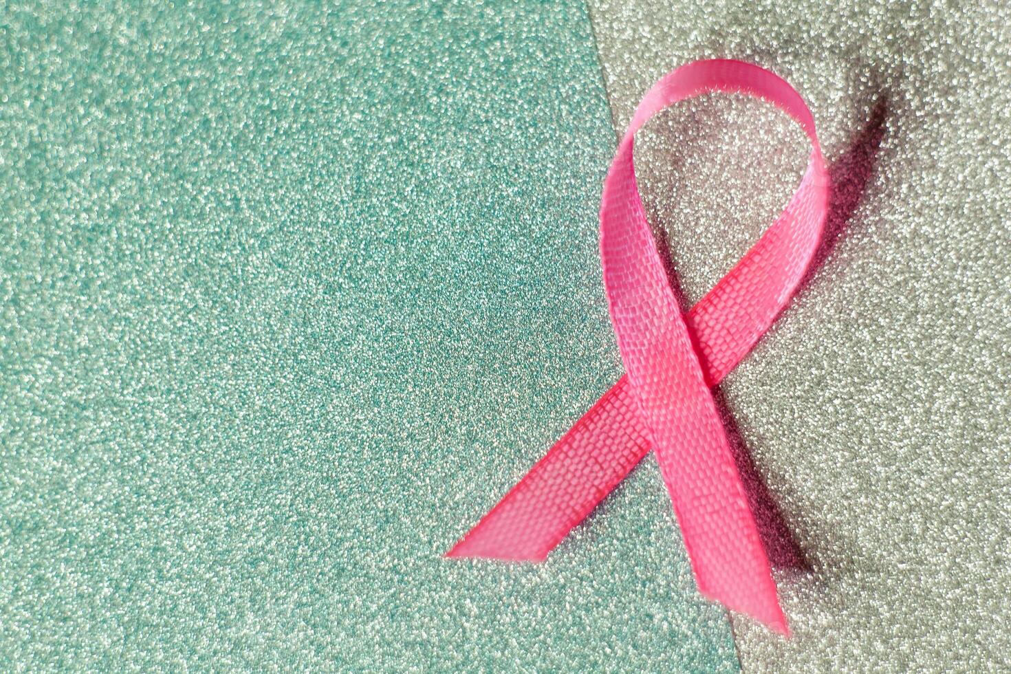 Pink ribbon for breast cancer awareness, symbolic bow color raising awareness on people living with women's breast tumor illness. bow isolated with clipping glitter blue background photo