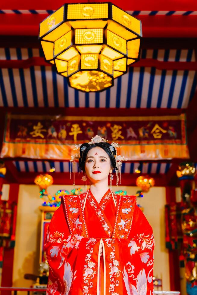 mujer vestir China nuevo año. retrato de un mujer. persona en tradicional traje. mujer en tradicional traje. hermosa joven mujer en un brillante rojo vestir y un corona de chino reina posando foto