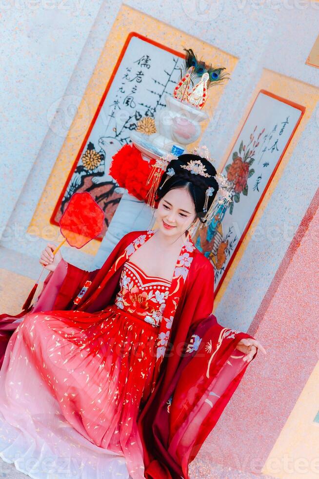 mujer vestir China nuevo año. retrato de un mujer. persona en tradicional traje. mujer en tradicional traje. hermosa joven mujer en un brillante rojo vestir y un corona de chino reina posando foto