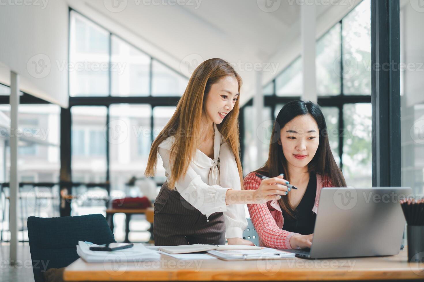 Business team analytics concept, Two engaged female colleagues discussing work projects on a laptop in a bright modern office setting. photo