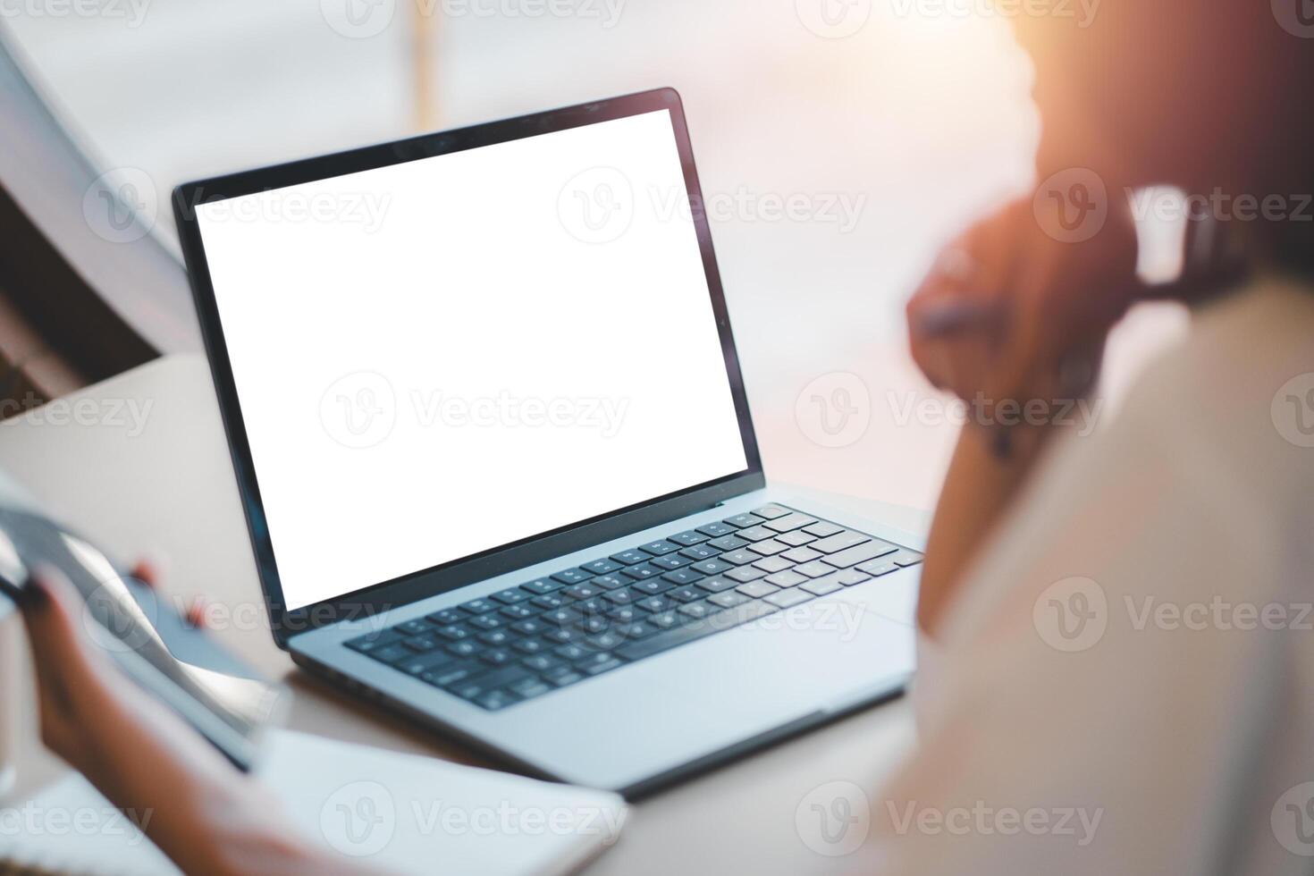 un enfocado profesional usos un moderno ordenador portátil con un blanco pantalla en un bien iluminado oficina configuración, exhibiendo potencial para negocio y tecnología temas foto