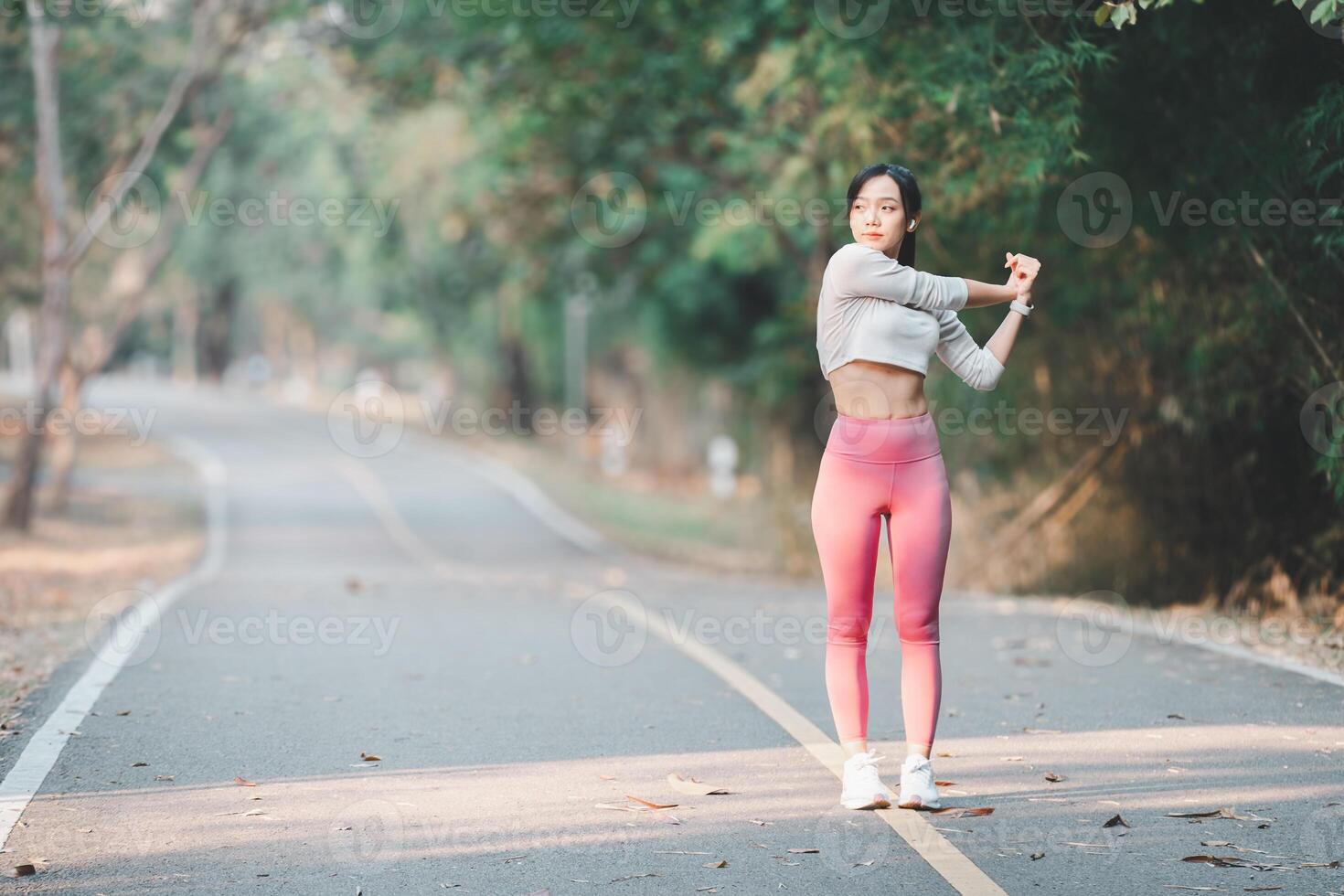 corriendo concepto, un centrado en el fitness mujer en ropa deportiva extensión su brazos antes de un rutina de ejercicio en un sereno parque ruta. foto