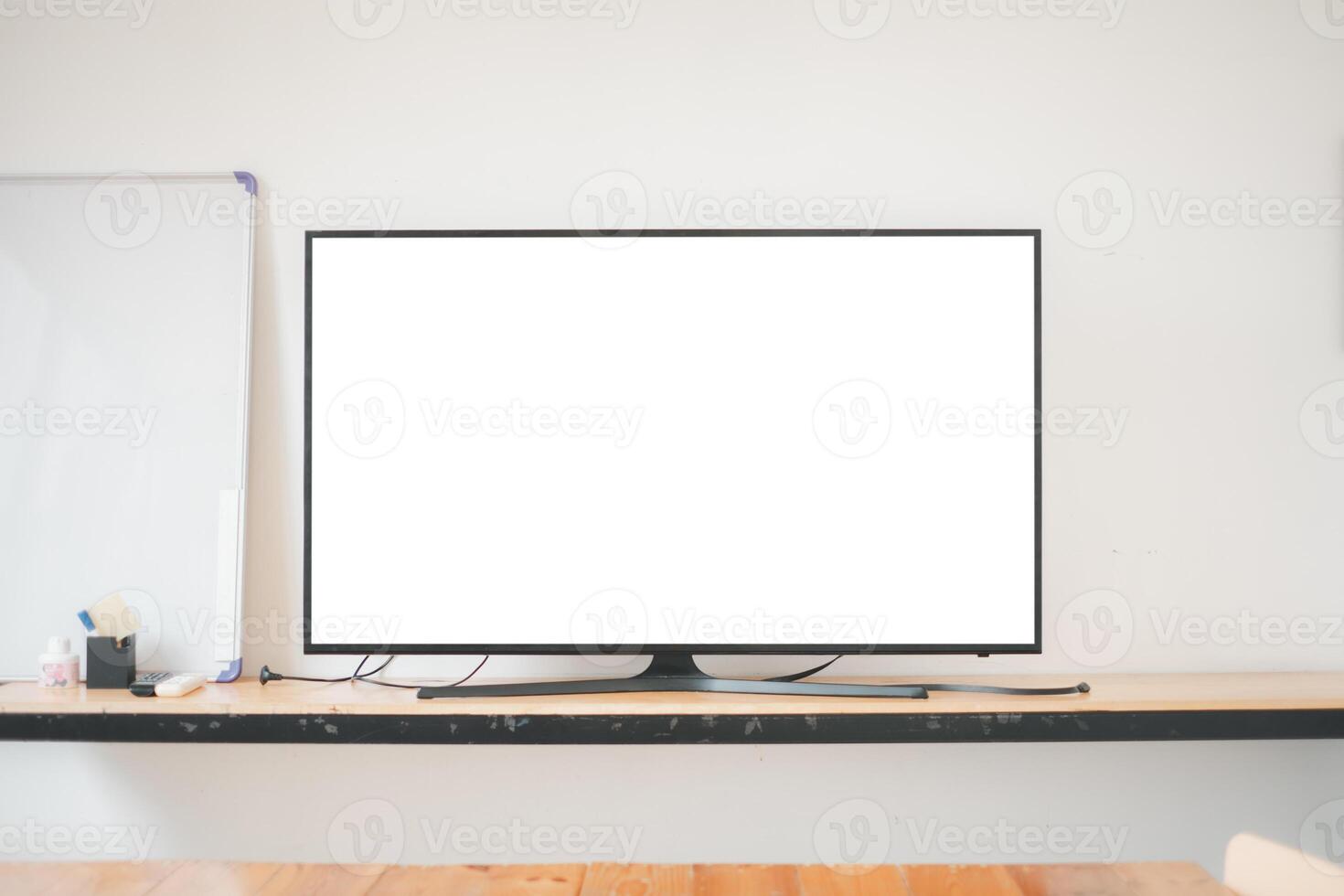 A sleek, modern computer monitor sits on a wooden office desk with a whiteboard in the background, ideal for a professional workspace. photo