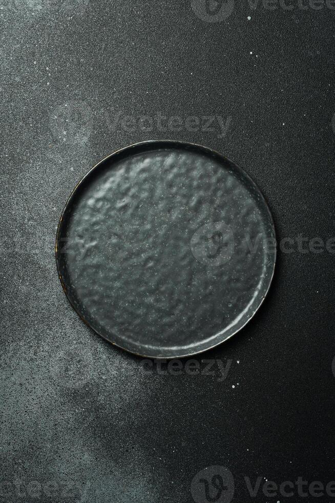 Black craft plate on dark stone table. Top view, copy space, Table setting. background for menu, layout, place for text , recipe background, food flat lay background photo