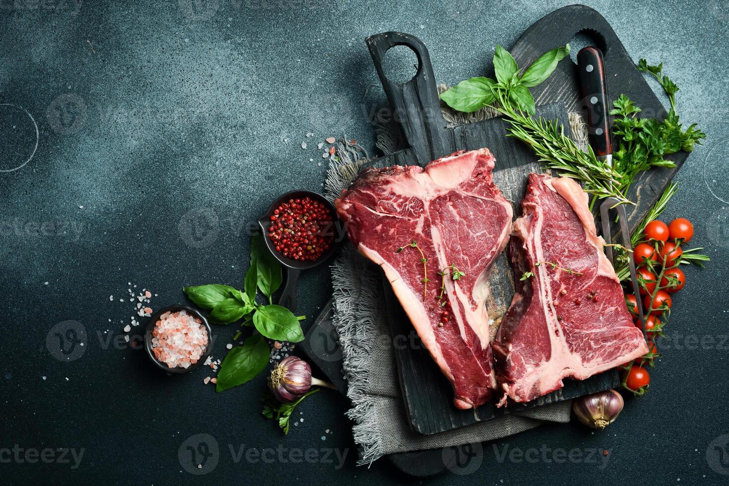 Two Raw T-bone Steak with fresh herbs and ready to cook. A piece of veal. photo