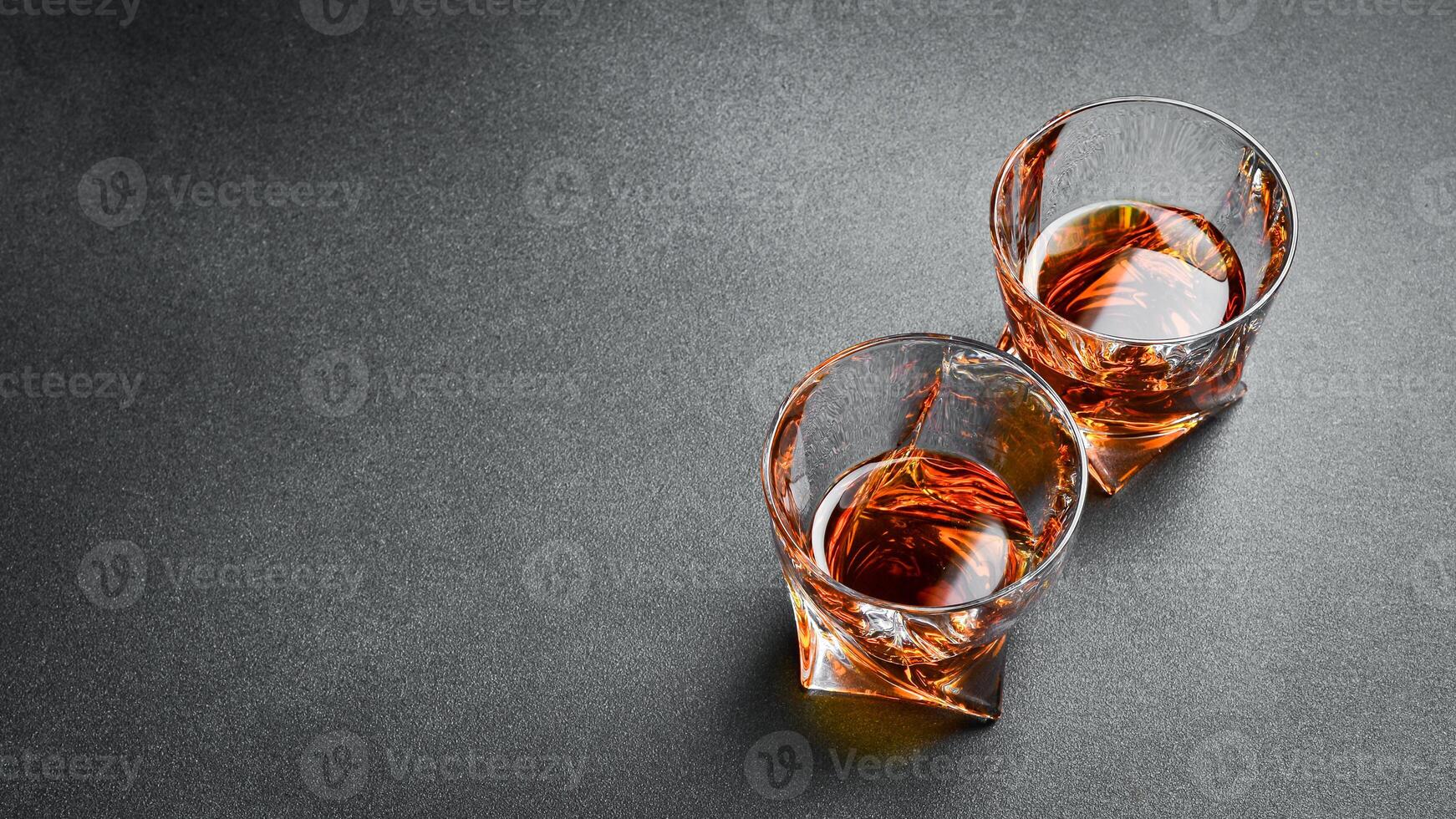 Two glasses of strong alcohol whiskey, rum or bourbon. Strong aged alcoholic drinks. photo