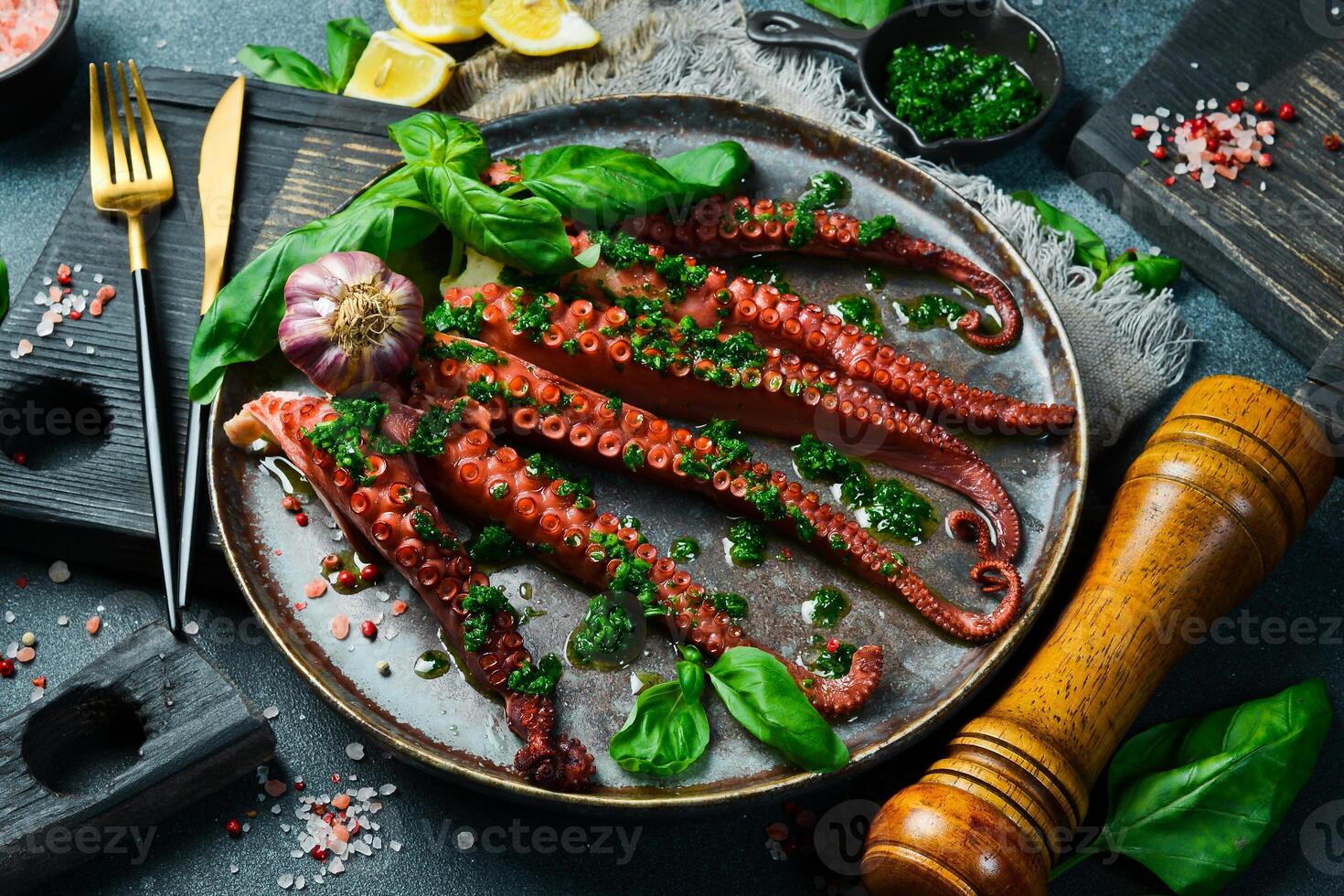 Grilled octopus with garlic and basil on a black stone plate. Fresh octopus cuttlefish dinner restaurant photo