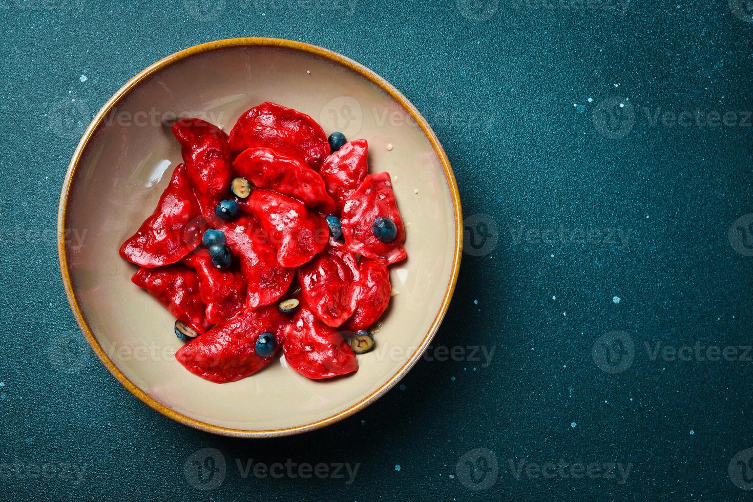 Dumplings with cherries, raspberries and salted caramel. On a black stone background. In a plate, close-up. photo