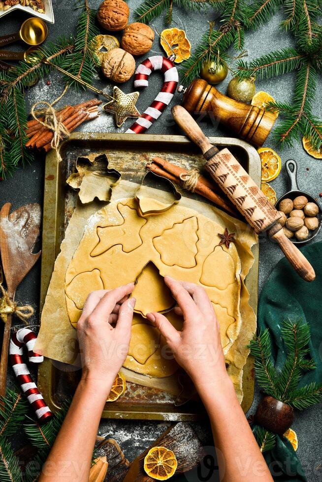 Navidad horneando concepto. hembra manos cortar fuera galletas desde el masa. ingredientes para horneando pan de jengibre. foto