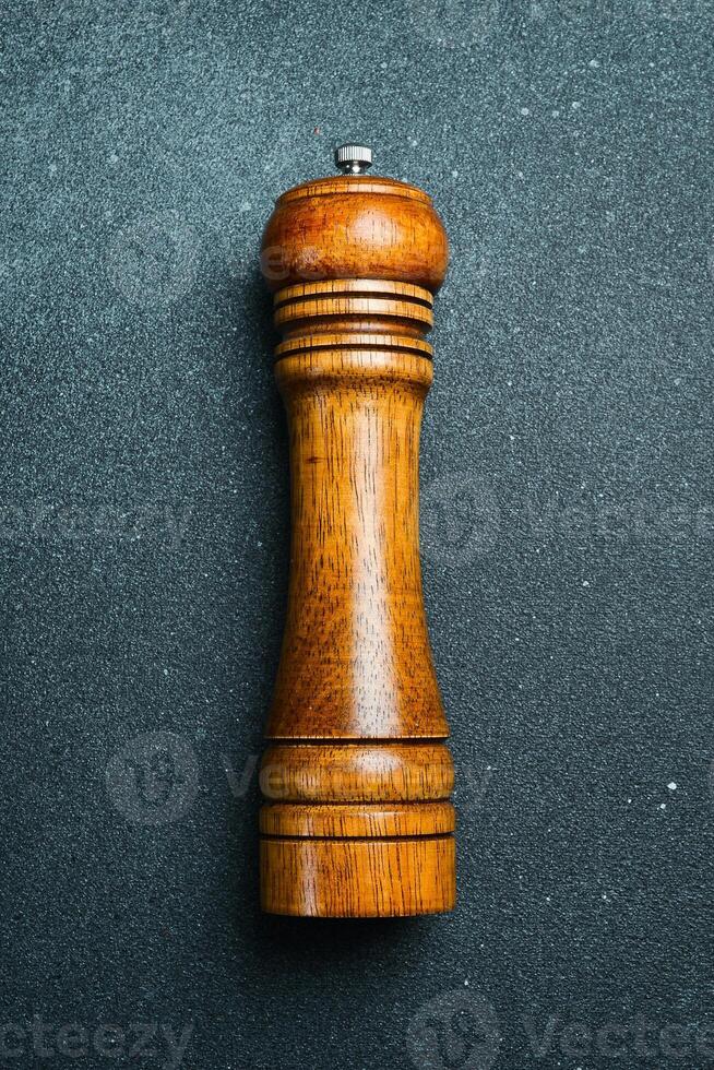 Wooden pepper mill. On a black slate background. Top view. photo