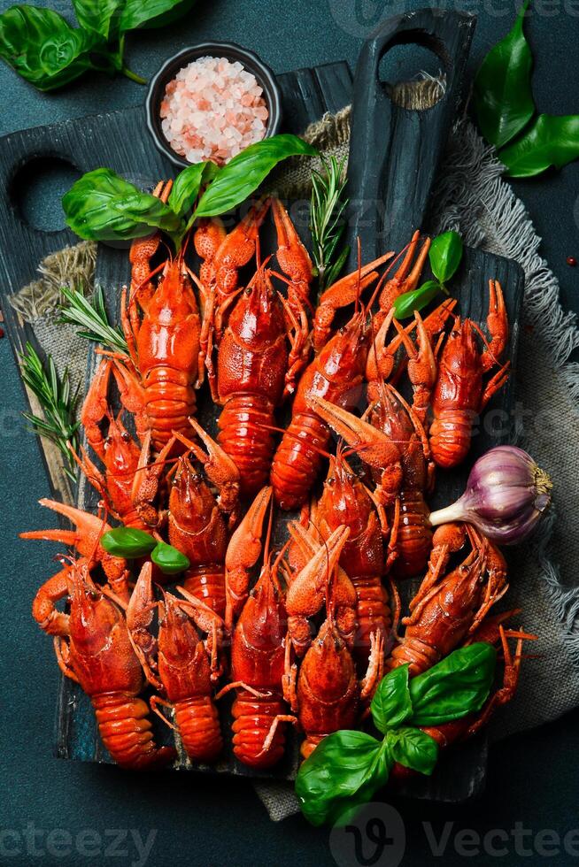 Crayfish. Red boiled crawfishes in a bowl with rosemary and spices. On a dark background. Free space for the recipe. photo