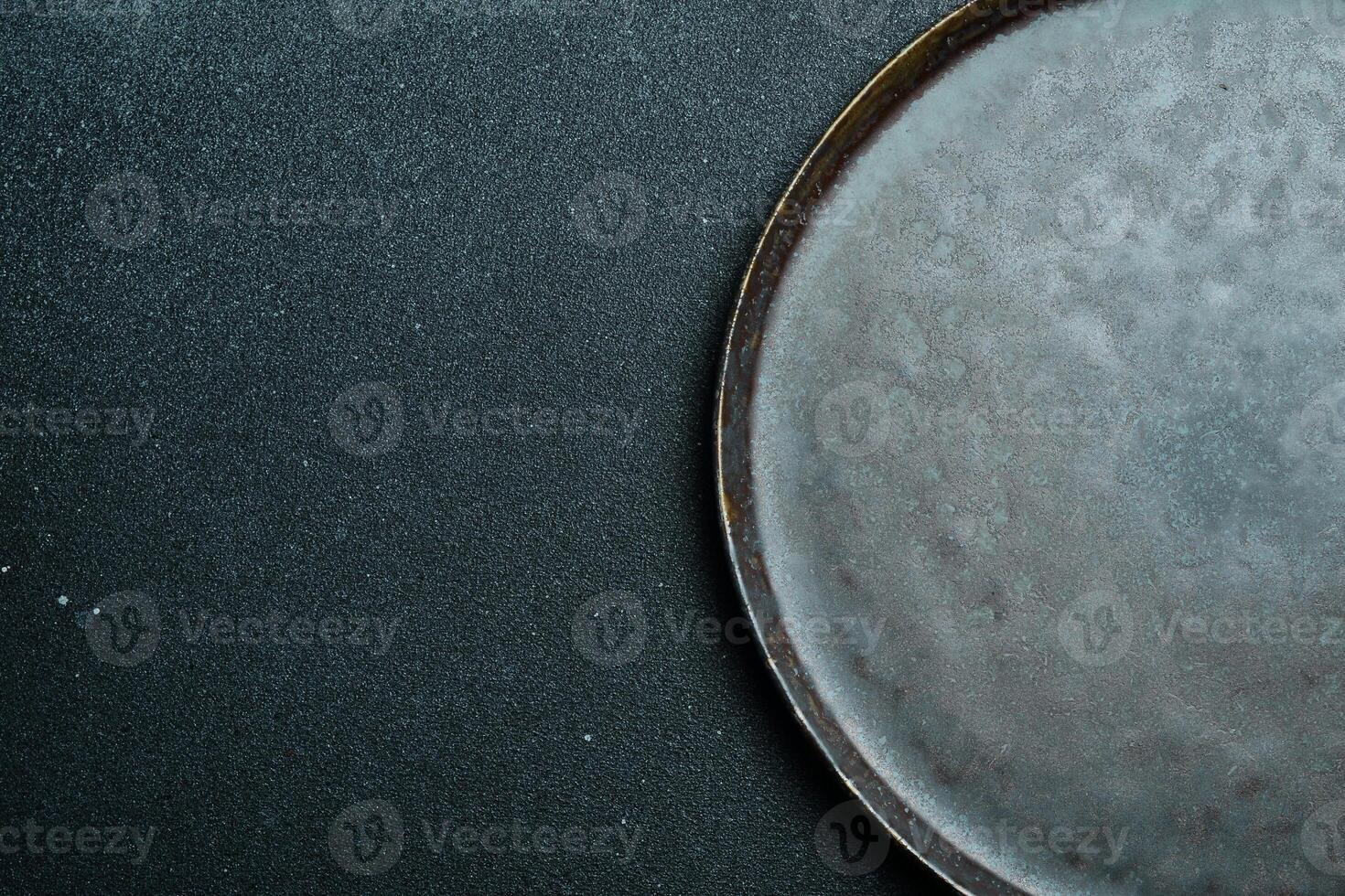 Black craft plate on dark stone table. Top view, copy space, Table setting. background for menu, layout, place for text , recipe background, food flat lay background photo