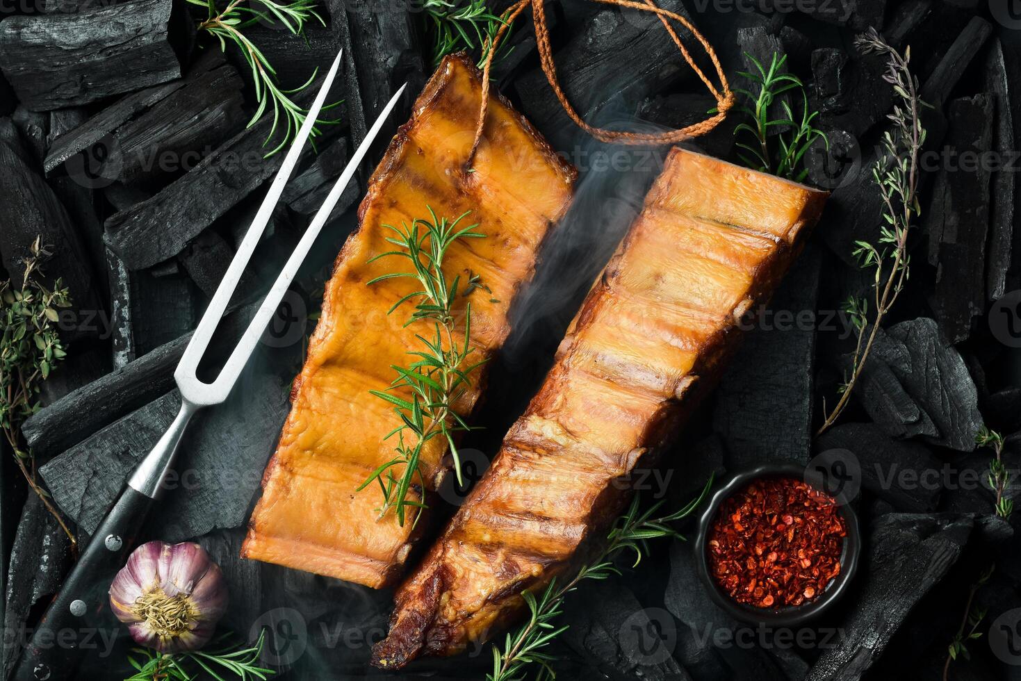 Smoked pork ribs with spices on a stone background. On a black stone background. Free space for the recipe. photo