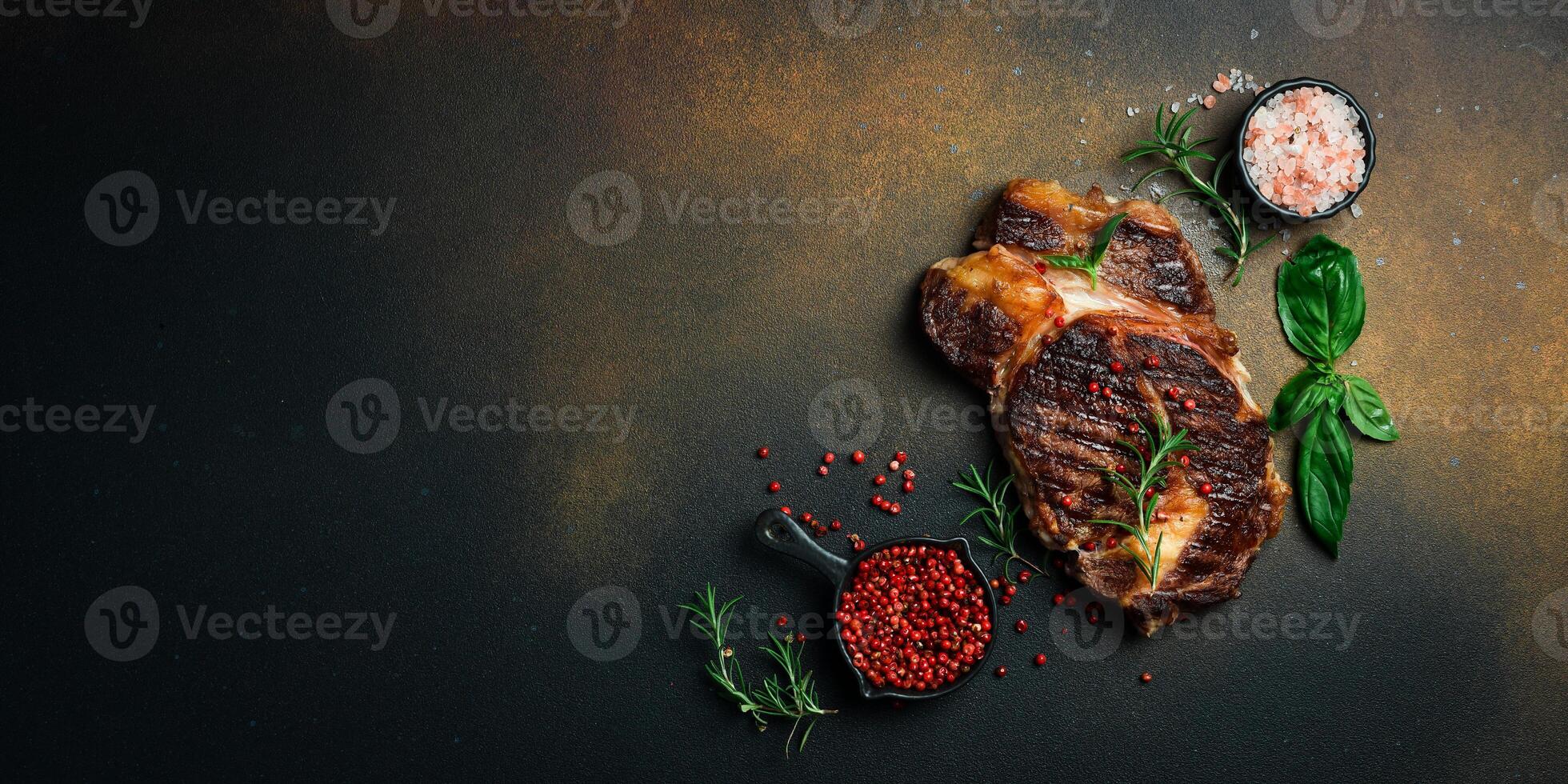 Grilled veal steak with rosemary on a dark brown background. Banner photo. Top view with copy space. Flat lay photo