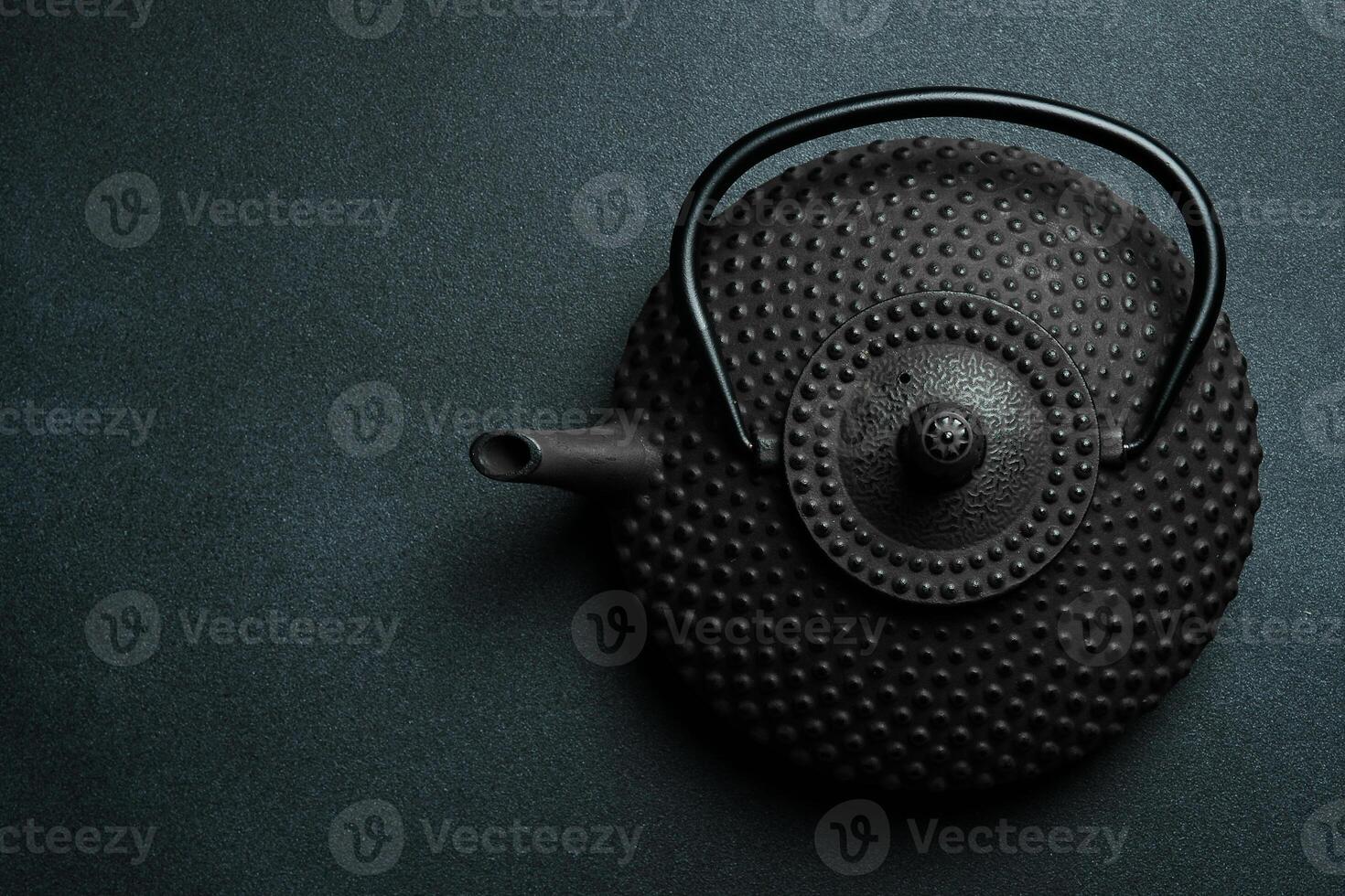 Black iron teapot for brewing tea. On a black stone background. Top view. Free space for text. photo