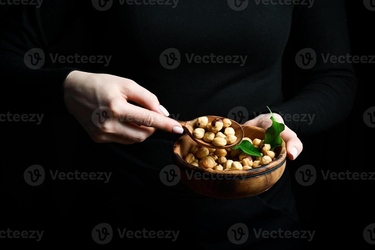A bowl of hazelnuts in the hands of a woman. Healthy high-calorie vegan food concept. Close up. photo