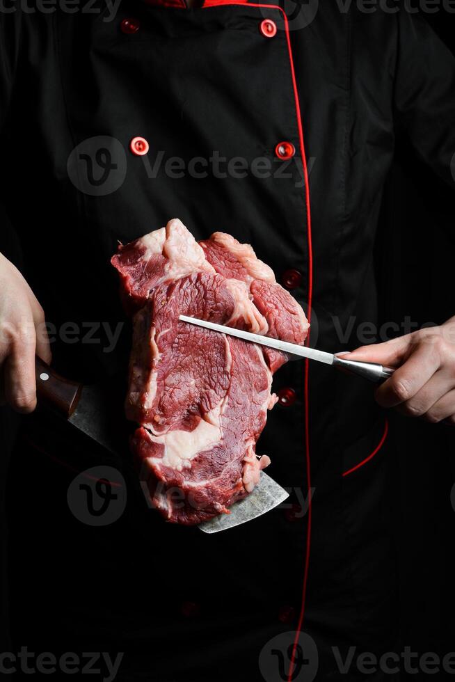 cropped shot of chef with fork and raw steak, on the background with free space for text design or logotype menu restaurant. Meat. On a black background. photo