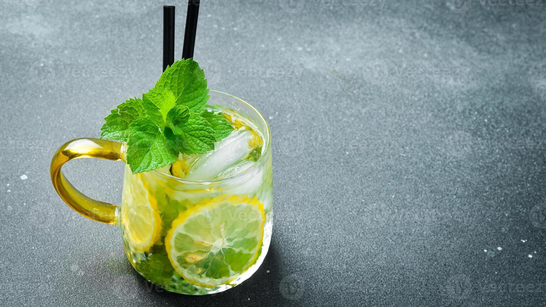 Refreshing summer alcoholic cocktail mojito with ice, lemon and mint. On a dark stone table. photo