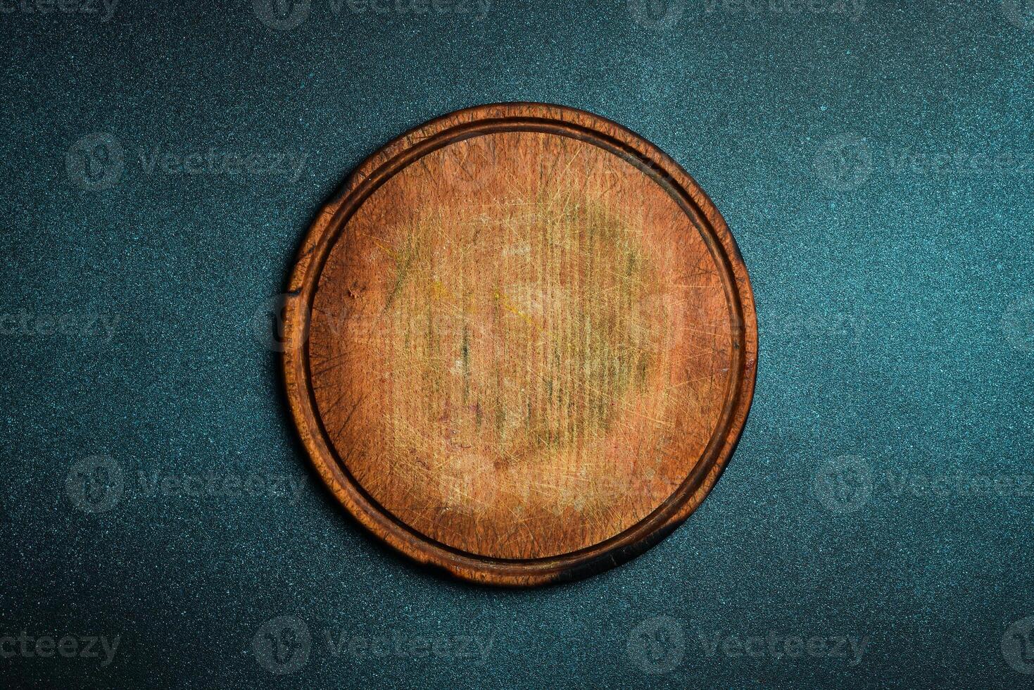 Kitchen round cutting board. Brown board. Kitchen utensils. On a dark background. photo