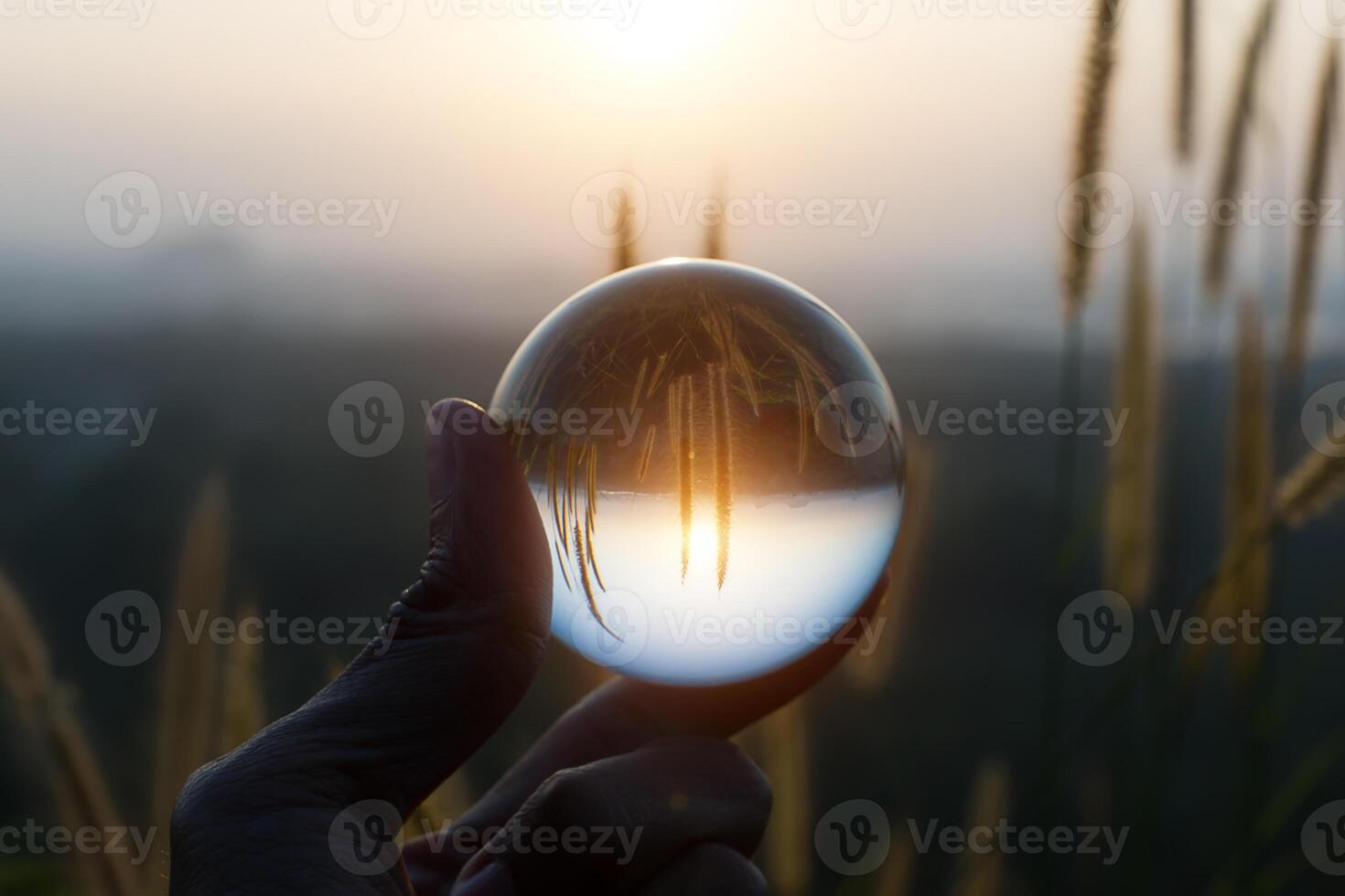 Crystal in hand at sunset with flower grass. photo