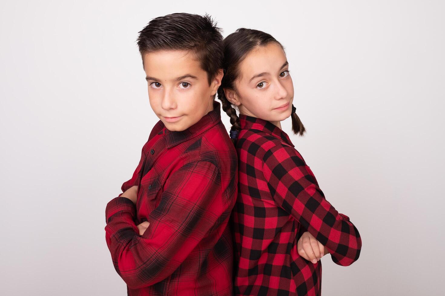 boy and girl with crossed arms posing back to back with challenging look photo