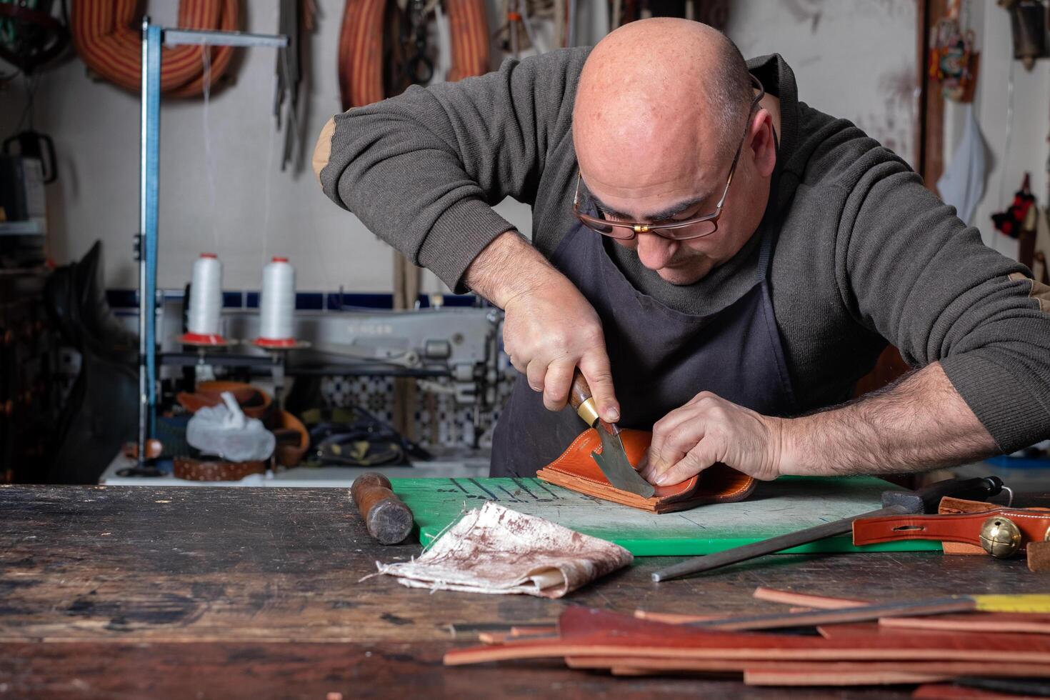 craftsman working the leather in his small saddlery workshop photo