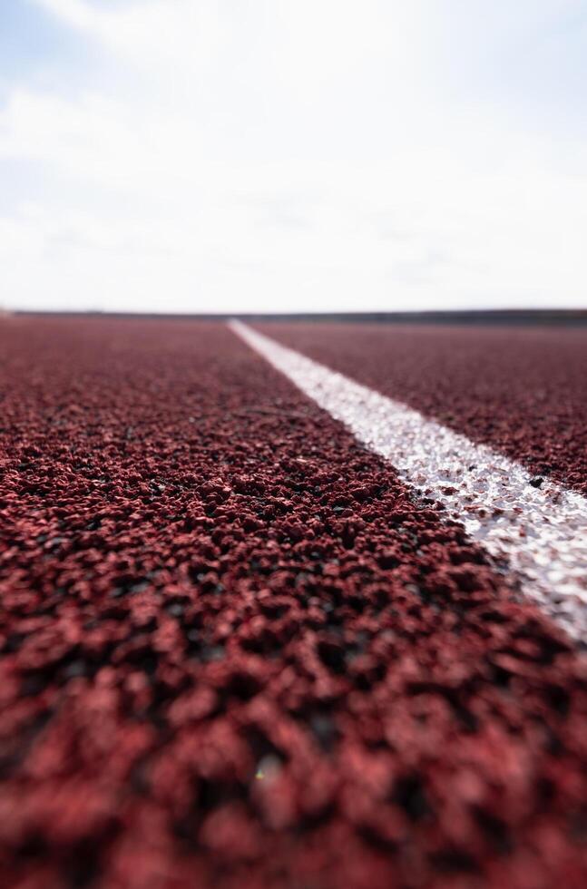 de cerca de un blanco carril línea en un rojo corriendo pista, con un borroso antecedentes. foto