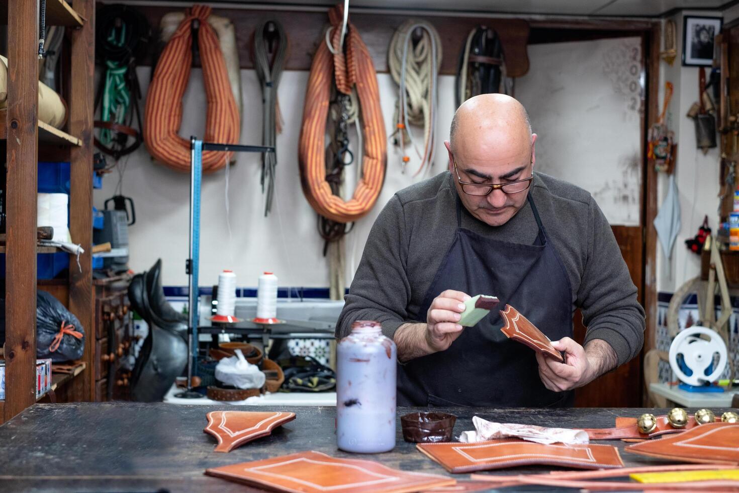 craftsman working the leather in his small saddlery workshop photo