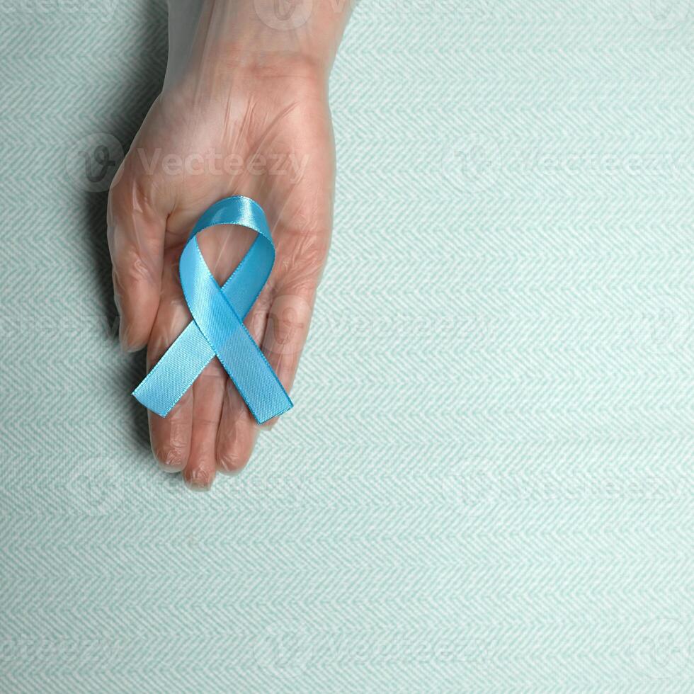 Blue cancer awareness ribbon with trail on blue background. concept of health and medicine photo