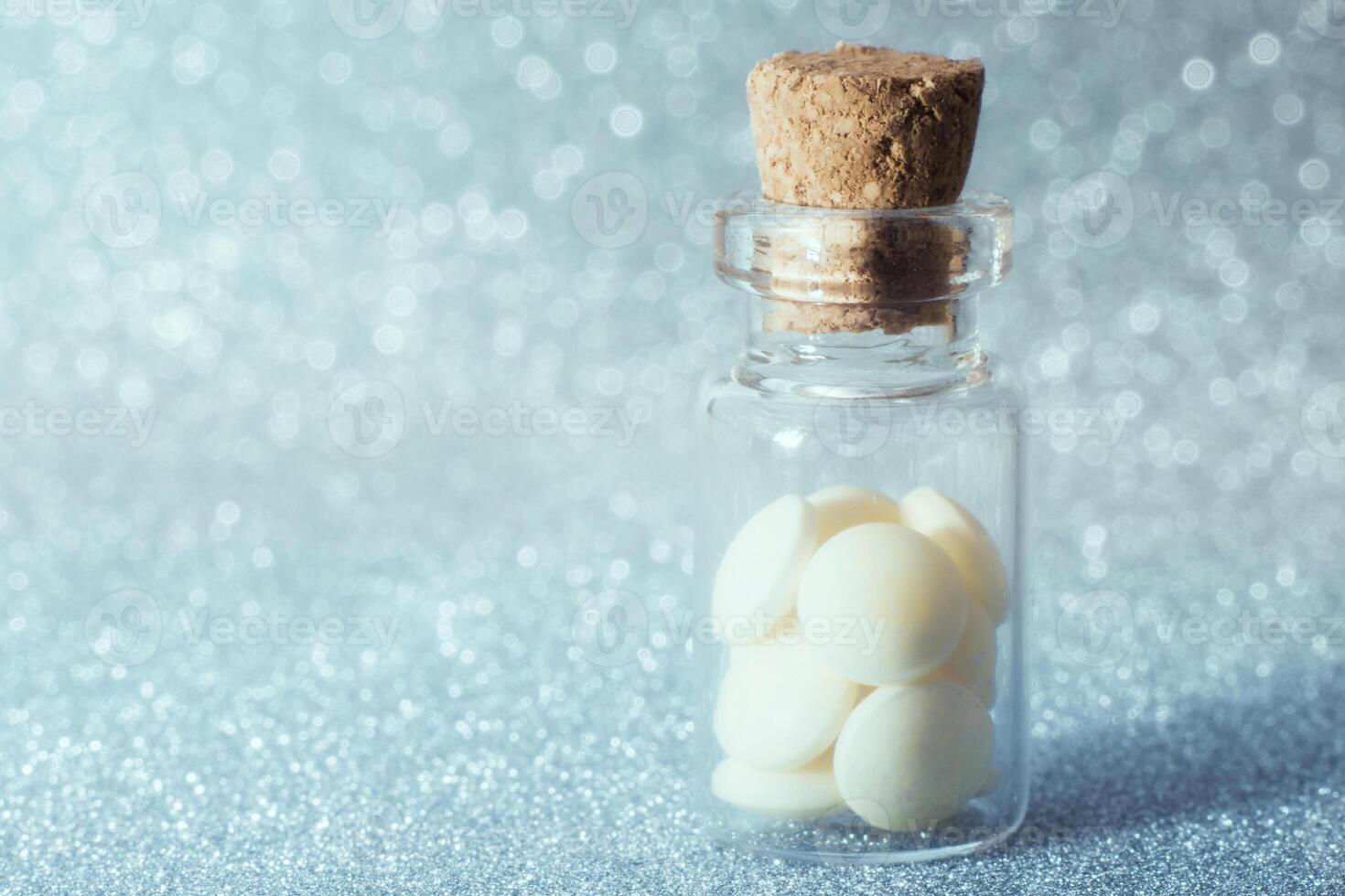 Pills in glass bottle spread on blue glitter, sparkles, sparkling background copy space. Global healthcare concept. Antibiotics drug resistance. Glimmer, sequins, bokeh effect. photo