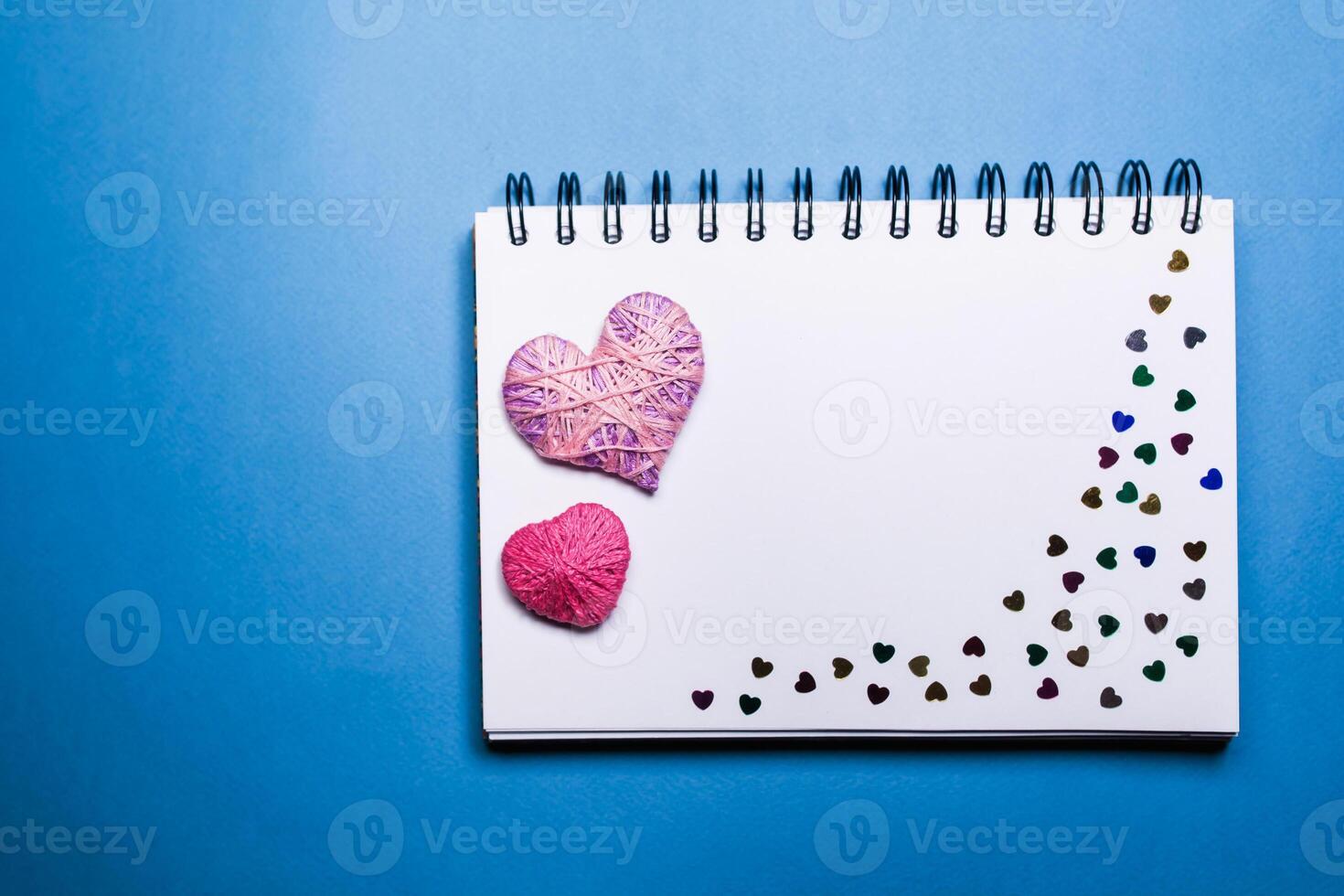 Simple blue background with a small purple red heart yn notebook. Place for text photo