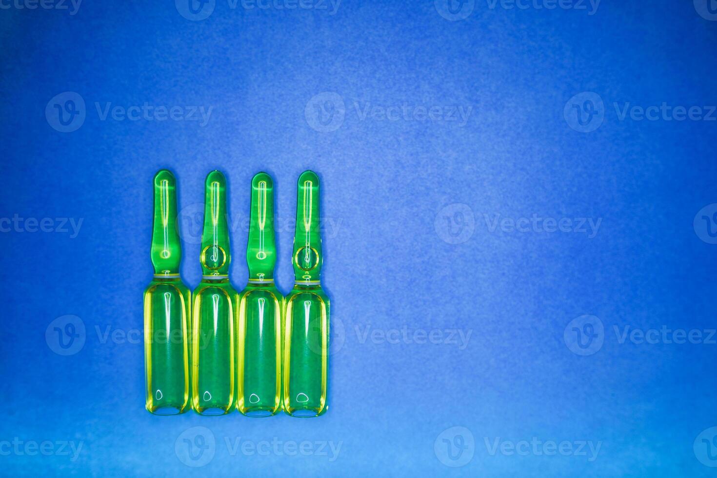 Medical ampules for injection isolated on blue background. Ampoules with botox, hyaluronic, collagen or vitamins photo