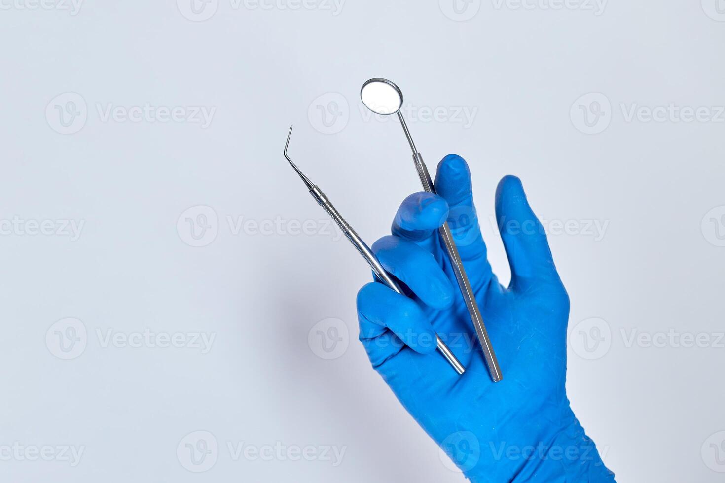 Cropped shot of professional dentist in medical gloves working with probe and mirror photo