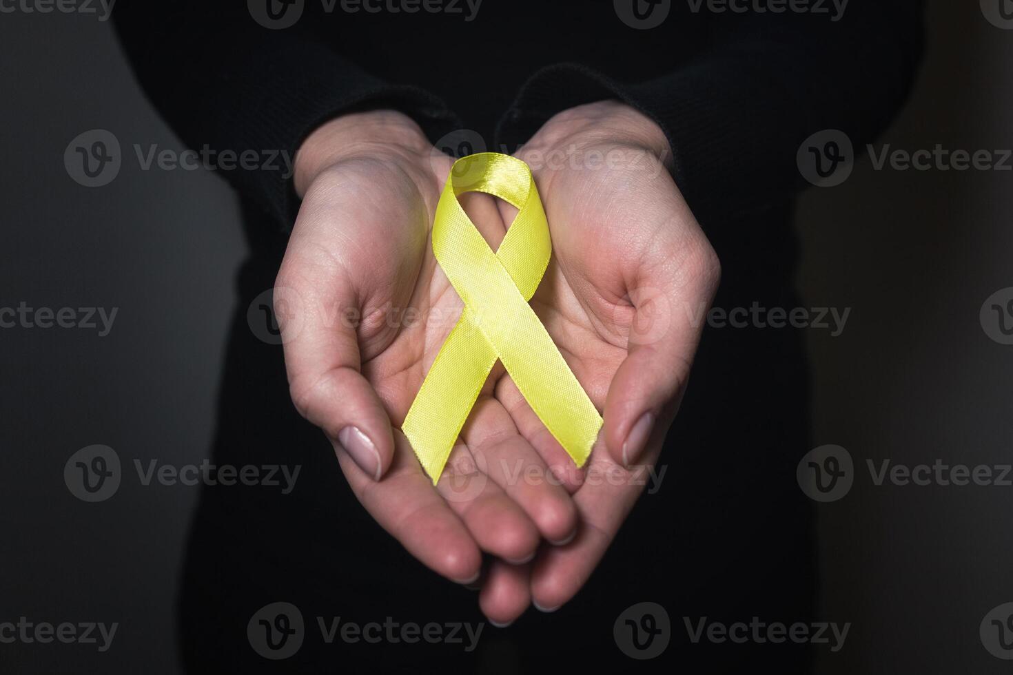 Gold ribbon for children as a symbol of childhood cancer awareness. yellow ribbon on hand photo