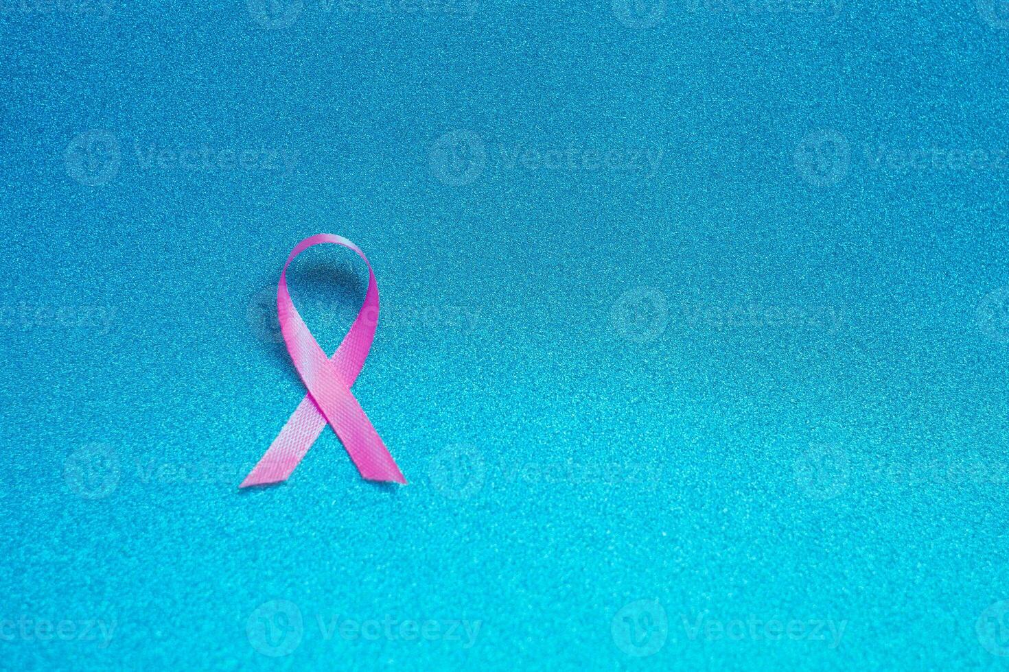 Pink ribbon for breast cancer awareness, symbolic bow color raising awareness on people living with women's breast tumor illness. bow isolated with clipping glitter blue background photo