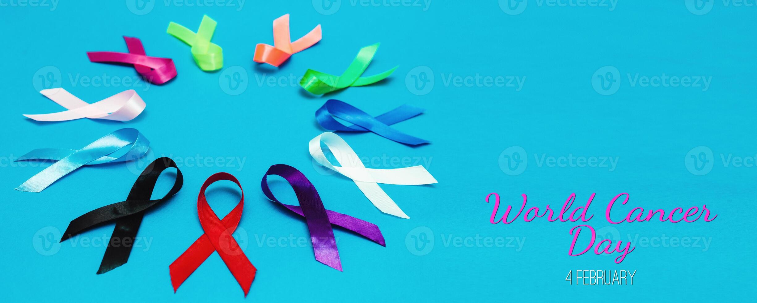 Paper with text WORLD CANCER DAY February 4 background. Colorful ribbons, cancer awareness. blue surface from above photo