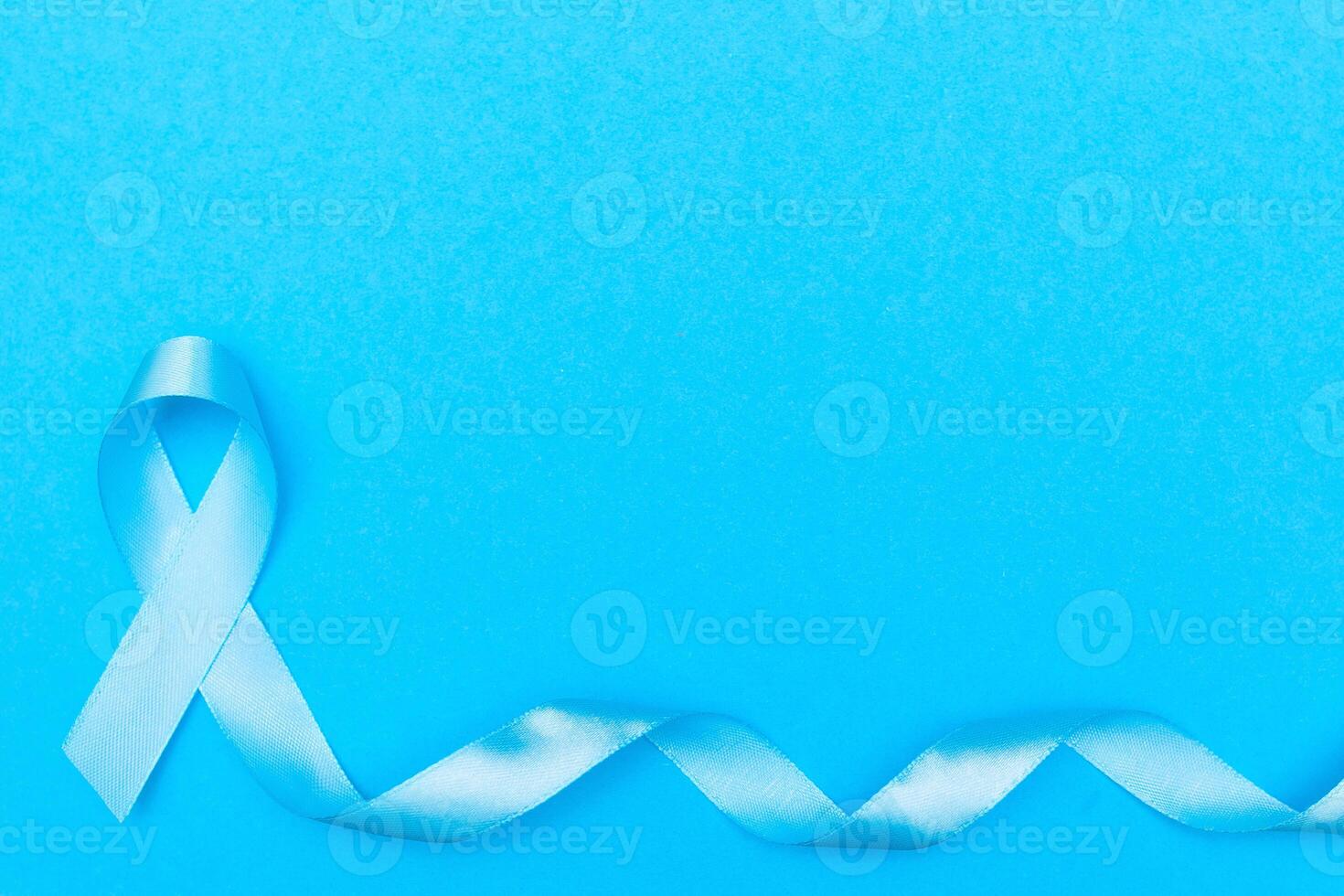 blue cancer awareness ribbon with trail on blue background. concept of health and medicine photo